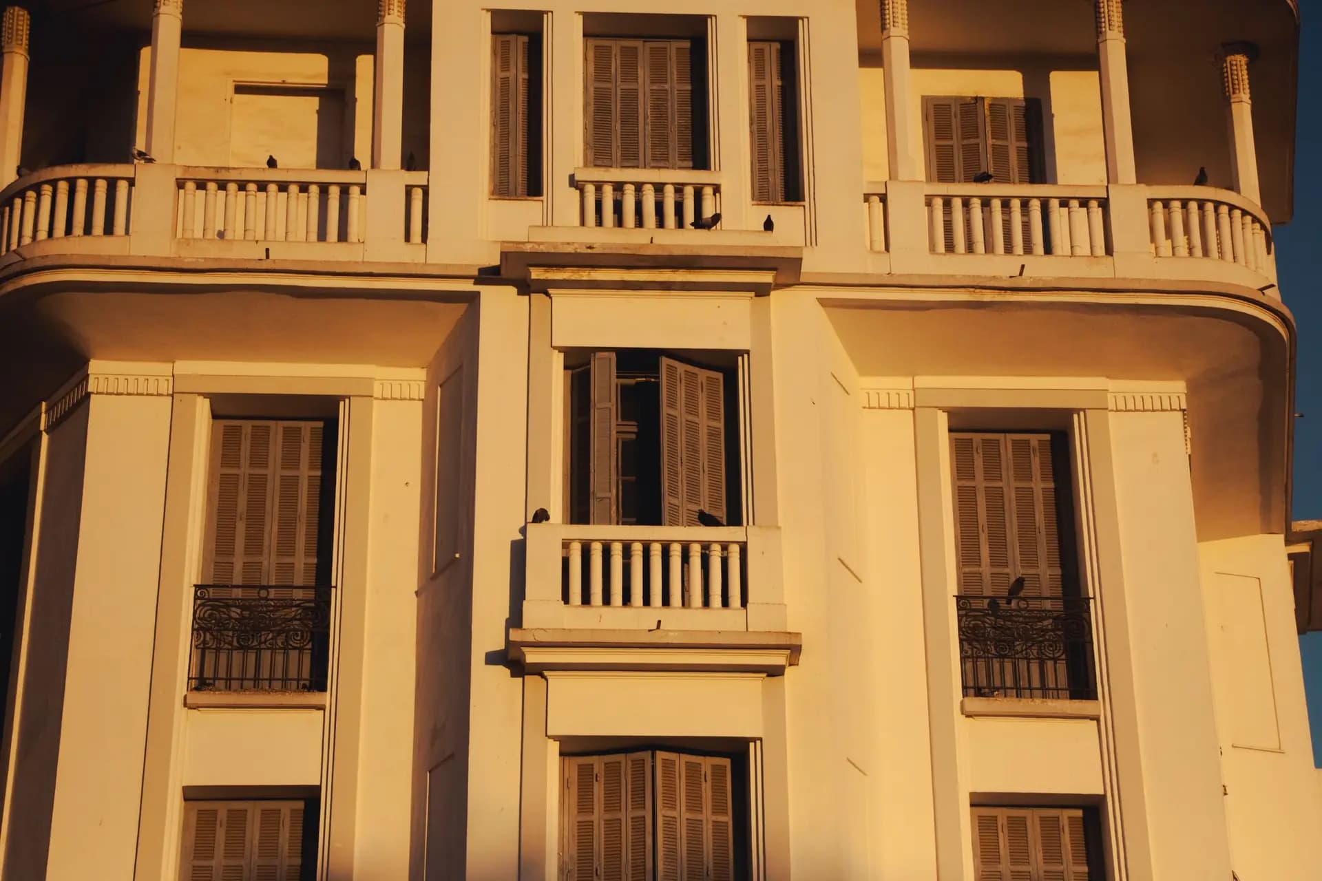 Façade d’un immeuble Art déco au Maroc : balcons, volets de bois et moulures dans la lumière chaude du soir